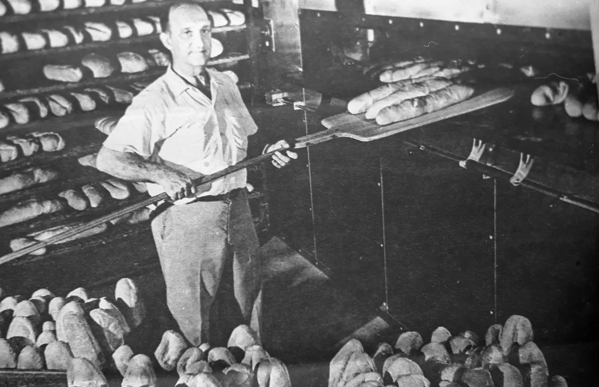 A Maranto baker pulling fresh Italian loaves from the hearth oven with a wooden peel